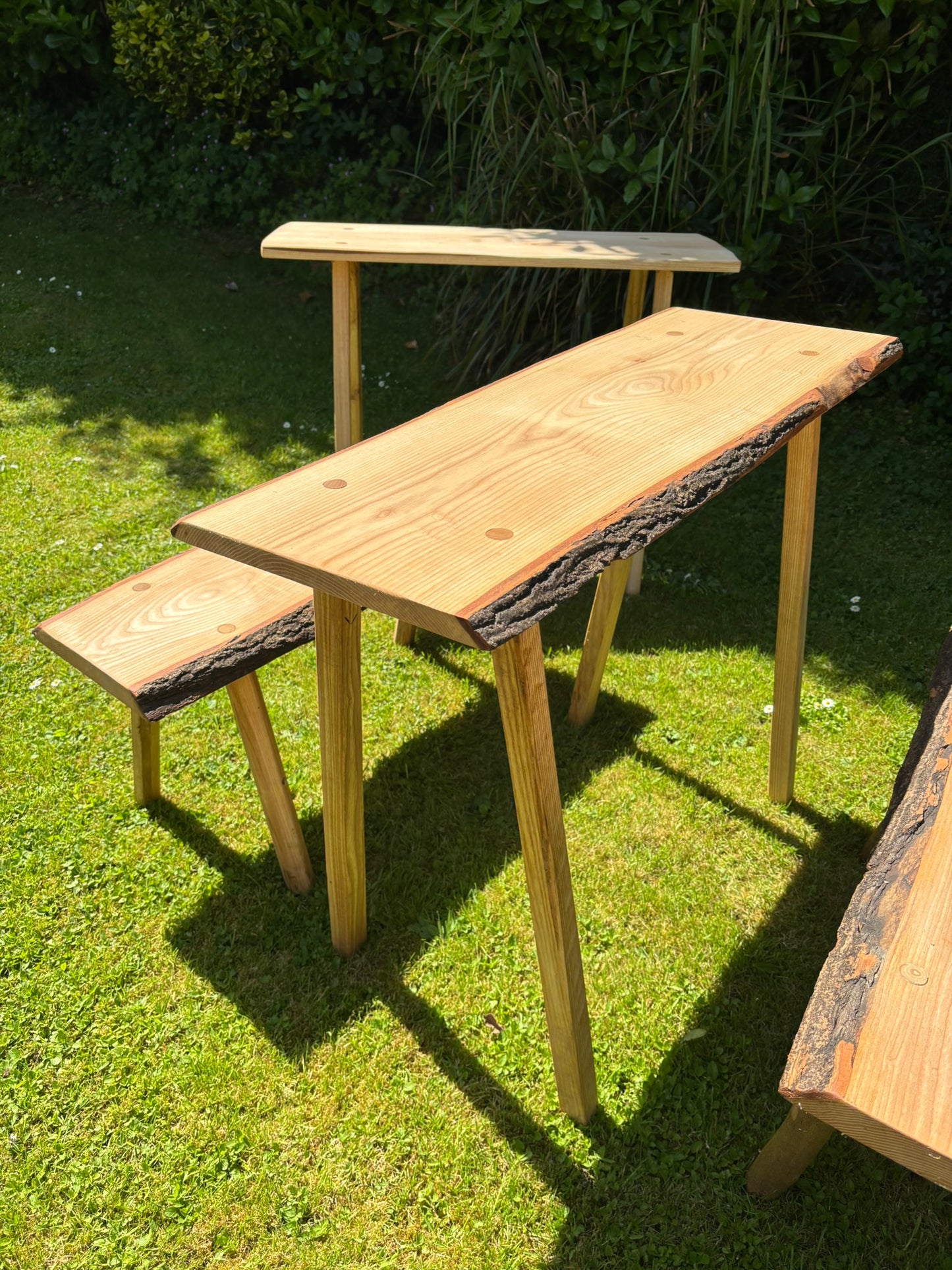 A rustic outdoor wooden table and bench set on a green grass lawn.