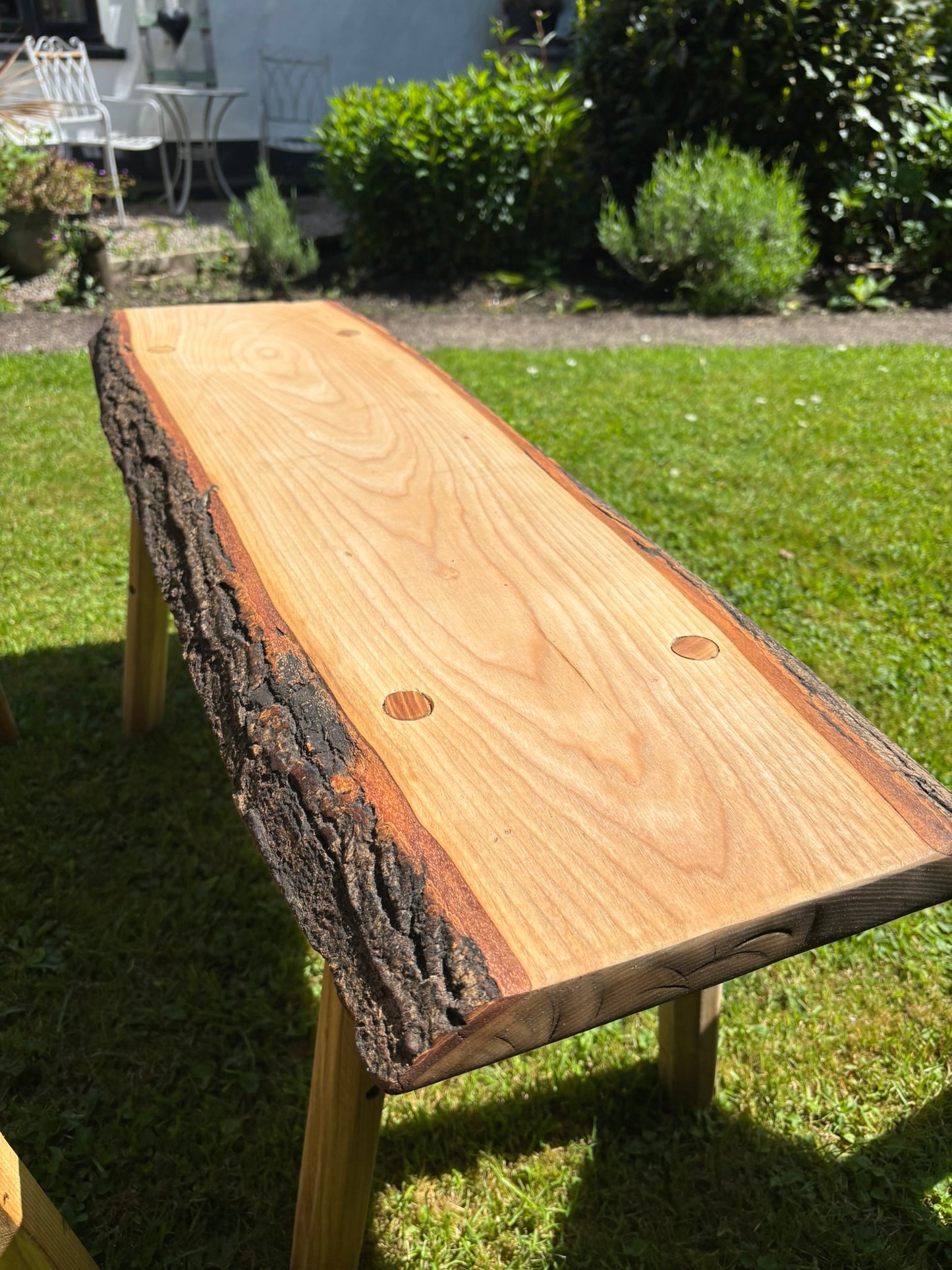 A live-edge wooden Viking bench with a natural bark-look side and visible wood grain.
