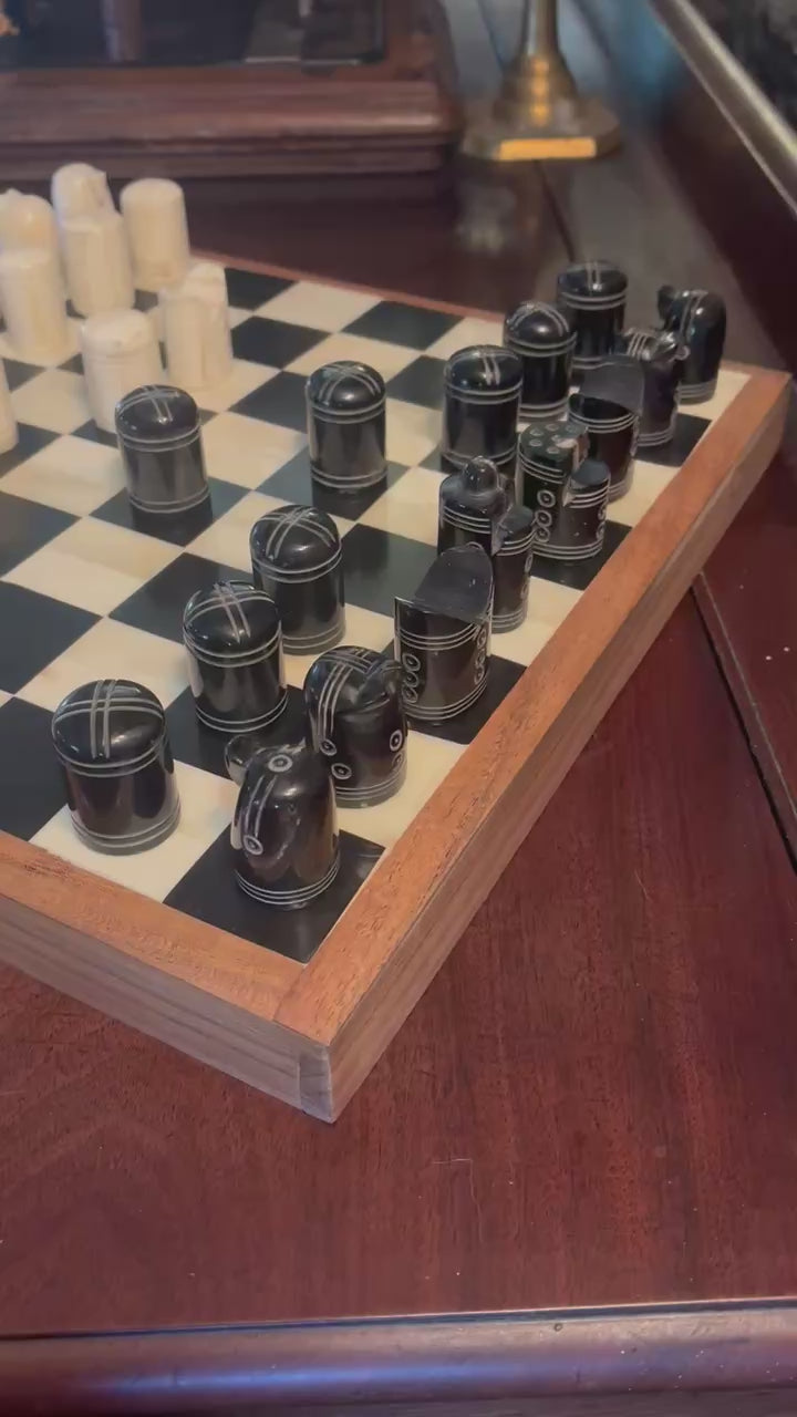 Close-up of a wooden chessboard with black and white pieces set up on a polished table.